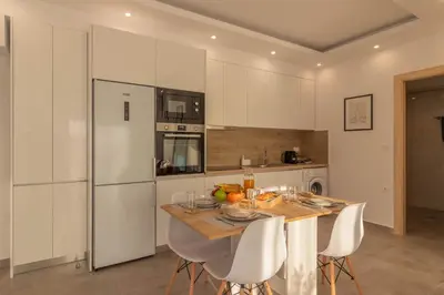 a kitchen with a wooden table and white appliances at Onda Blu in Rhodes Town