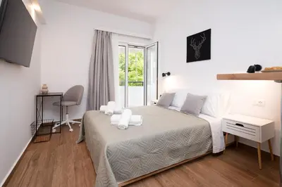 a white bedroom with a bed and a window at Gravity Downtown Balcony Studio in Rhodes Town