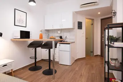 a kitchen with white cabinets and a counter with stools at Gravity Downtown Balcony Studio in Rhodes Town