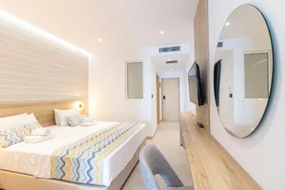 a bedroom with a bed and a mirror and a chair at Sunrise Hotel in Pefki Rhodes