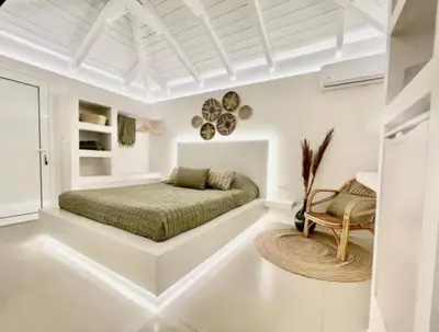 a white bedroom with a bed and a chair at White House Luxury Apartment of Rhodes in Kremasti