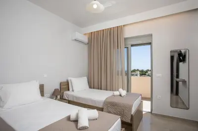 a hotel room with two beds and a balcony at Twin Villas Gennadi in Gennadi