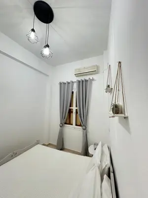 a white bedroom with a bed and a window at Seaside escape in Symi