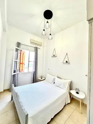 a white bedroom with a bed and a window at Seaside escape in Symi