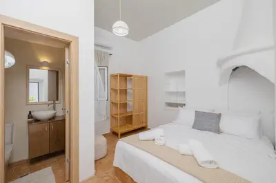 a white bedroom with a large bed and a bathroom at Cleopatra's Backyard in Rhodes Town