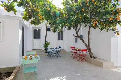 a patio with tables and chairs under an orange tree at Cleopatra's Backyard in Rhodes Town