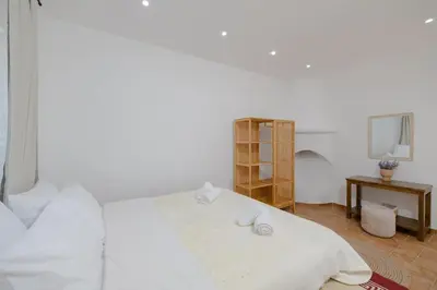 a bedroom with a white bed and a table at Cleopatra's Backyard in Rhodes Town