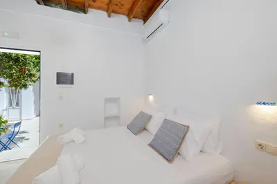 a white bedroom with a bed and a window at Cleopatra's Backyard in Rhodes Town