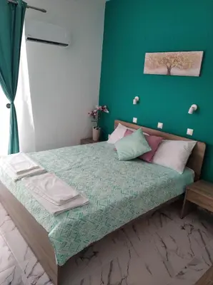 a bedroom with a bed with a green wall at Apollon Stegna Studios in Archangelos