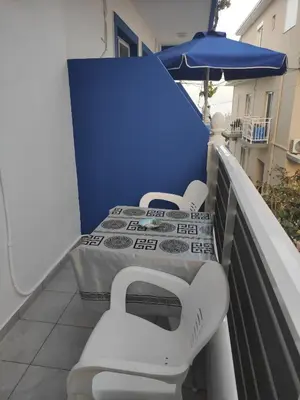 two beds on a balcony with an umbrella at Apollon Stegna Studios in Archangelos