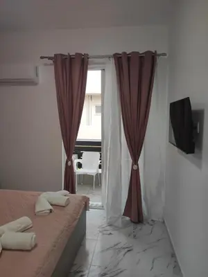 a bedroom with a bed and a window with curtains at Apollon Stegna Studios in Archangelos