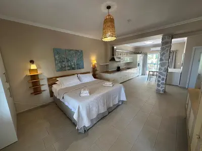 a bedroom with a large bed and a kitchen at Katalyma Thalassa in Ixia