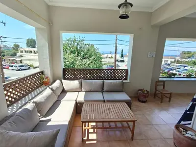 a living room with a couch and two large windows at Katalyma Thalassa in Ixia