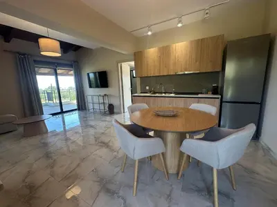 a kitchen with a table and chairs and a refrigerator at Katalyma Vouno in Ialyssos