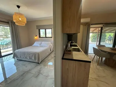 a bedroom with a bed and a kitchen with a table at Katalyma Vouno in Ialyssos