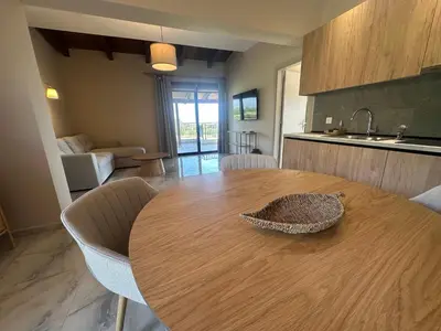 a kitchen with a wooden table with chairs and a couch at Katalyma Vouno in Ialyssos
