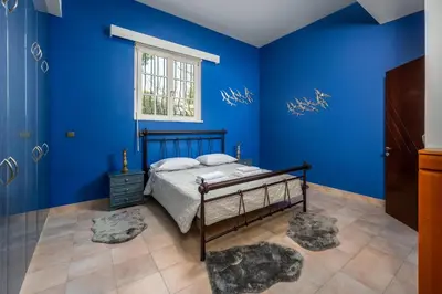 a blue bedroom with a bed and a window at Diamanti Villa Prime Location in Rhodes Town