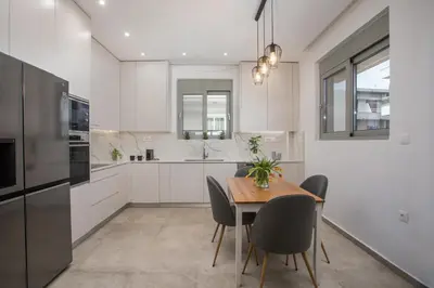 a kitchen with white cabinets and a wooden table and chairs at Casadi City Apartment in Rhodes Town