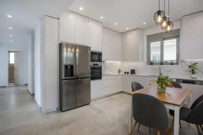 a kitchen with a table and a stainless steel refrigerator at Casadi City Apartment in Rhodes Town