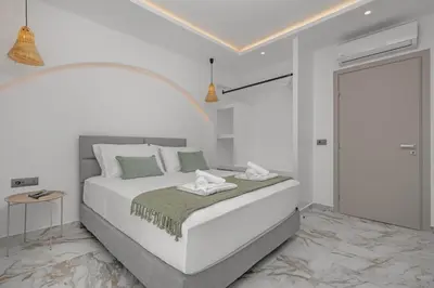 a white bedroom with a large white bed with green pillows at Arfna Villas in Afantou