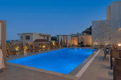 a large swimming pool on a patio with chairs at Arfna Villas in Afantou