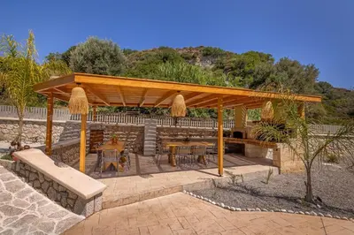 a wooden pergola with tables and chairs on a patio at Arfna Villas in Afantou