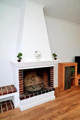 a living room with a brick fireplace with two plants at Dionysus Apartment in Rhodes Town