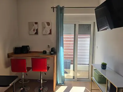a kitchen with a table and two red chairs at The cozy nest in Rhodes in Rhodes Town