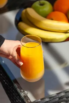a person holding a glass of orange juice next to fruit at Casa Aurora Rhodes in Rhodes Town