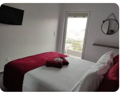 a bedroom with a bed with a red blanket and a window at Rhodos City in Rhodes Town