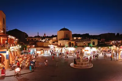 a group of people walking around a city at night at Rhodos City in Rhodes Town
