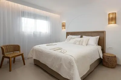 a bedroom with a large bed and a chair at Paradiso Luxury Beachfront Villa in Gennadi