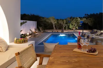 a table with wine glasses and a bottle of wine next to a pool at Paradiso Luxury Beachfront Villa in Gennadi