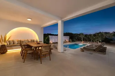 a dining room with a table and a swimming pool at Paradiso Luxury Beachfront Villa in Gennadi