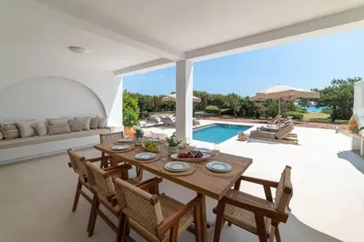 a dining room with a table and chairs and a pool at Paradiso Luxury Beachfront Villa in Gennadi