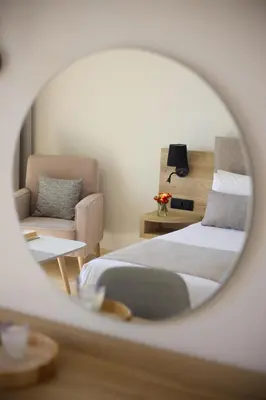 a bedroom with a bed and a chair and a mirror at Kiotari Miraluna Beach Resort in Kiotari
