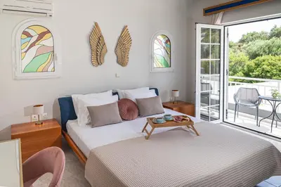 a bedroom with a bed with a table and windows at Maio Seaview & Sunset Stay in Kremasti Rhodes in Kremasti
