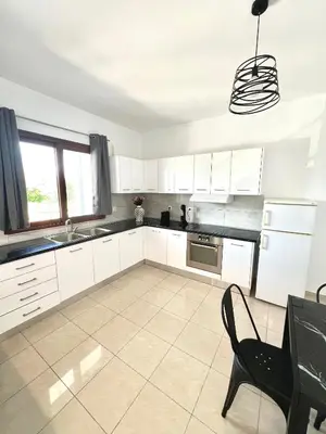 a kitchen with white cabinets and a black chair at KIDONIA luxury villa in Archangelos