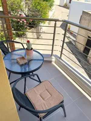 a table and chair on a balcony with a table and a cactus at Vasilias House in Apóllona