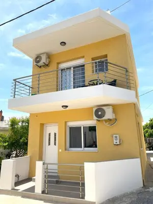 a yellow house with a balcony at Vasilias House in Apóllona