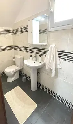 a white bathroom with a toilet and a sink at Vasilias House in Apóllona