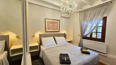 a bedroom with a bed with a chandelier and a window at Old Town Pearl in Rhodes Town
