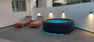 a patio with a hot tub and two chairs at Castalia Naiades Suites in Ialyssos