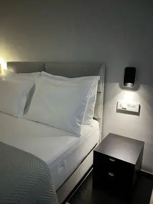 a bedroom with a bed with white pillows and a night stand at Castalia Naiades Suites in Ialyssos