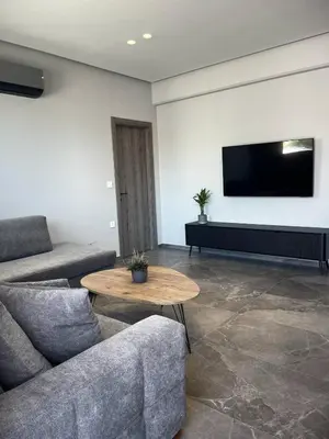 a living room with a couch and a table and a tv at Castalia Naiades Suites in Ialyssos