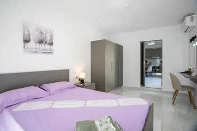 a white bedroom with a purple bed and a desk at Aelia House in Kalithies