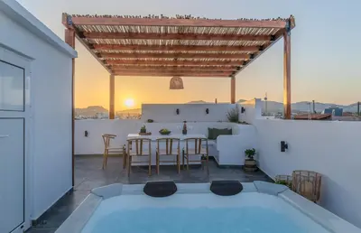 a patio with a table and chairs on a roof at Celestial Acropolis View in Archangelos