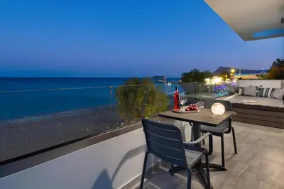 a table and chairs on a balcony with a view of the ocean at Elysian Luxury Residence in Vrachonisída touArchangélou