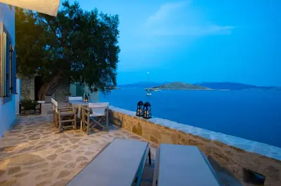 a patio with tables and chairs overlooking the water at Villa Annouska in Halki
