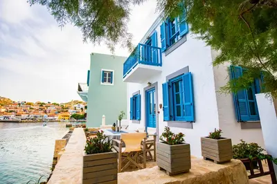 a house by the water with blue shutters at Villa Annouska in Halki